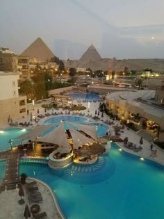 an aerial view of the pool and surrounding buildings at night, with pyramids in the background