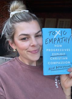 a woman holding up a book in front of her face and smiling at the camera