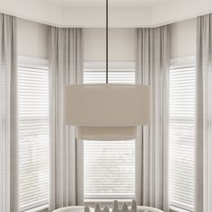 a living room with two couches and a table in front of large windows that have blinds on them