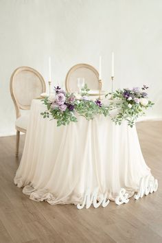 the table is set with two chairs and there are flowers on it, along with candles