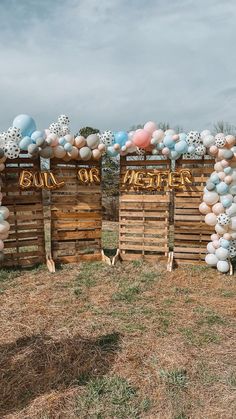 two wooden pallets with balloons attached to them on the grass and some trees in the background