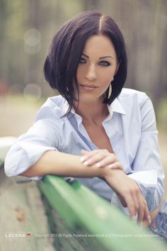 a woman sitting on a bench with her arms crossed and looking off to the side