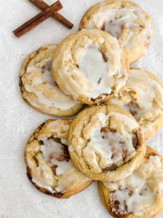 a pile of cookies with white icing and cinnamon sticks