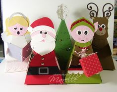 three paper christmas trees with santa and mrs claus on them, one is holding a gift bag