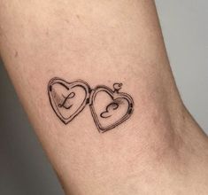 two heart shaped tattoos on the left side of the arm, one with an arrow