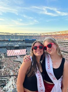 two women wearing red sunglasses are posing for a photo in front of an empty stadium