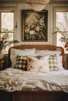 a bed with white sheets and pillows in front of two large paintings on the wall