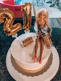 a barbie doll sitting on top of a birthday cake with balloons in the shape of numbers