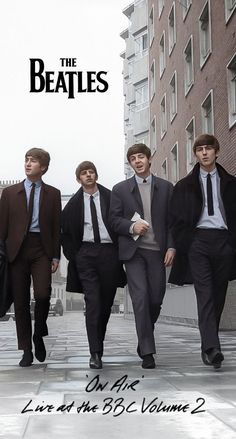 the beatles walking down a city street in suits and ties, with buildings in the background