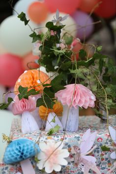 small vases filled with flowers and greenery sit on a table in front of balloons