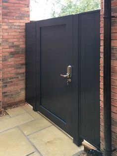 a large black door is open on a brick wall and there are no people around it