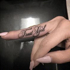 two hands with tattoos that say trust god and one has a finger tattoo on it