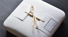 a gift wrapped in white paper and tied with gold ribbon