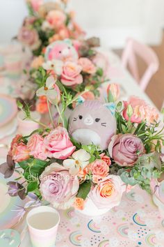 the table is set with pink flowers and an adorable stuffed animal in it's centerpiece