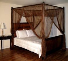 a four poster bed with mosquito netting on the headboard and foot board, in a bedroom