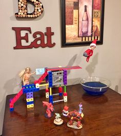 a table with toys on it in front of a sign that says eat and an elf is jumping over the top