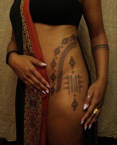 a woman's stomach with tattoos on it and an orange scarf around her waist