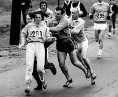 a group of men running down a street next to each other on top of a sidewalk