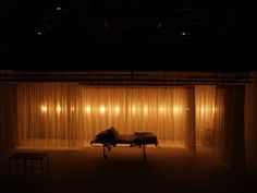 a dimly lit room with curtains and a bed in the foreground at night time