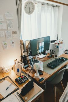 an office desk with two computers on it and papers all over the place in front of the window