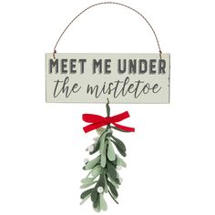 a sign that says meet me under the mistletoe hanging from a red ribbon