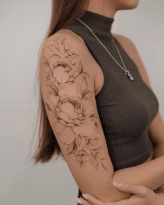 a woman with a flower tattoo on her arm and shoulder is posing for the camera