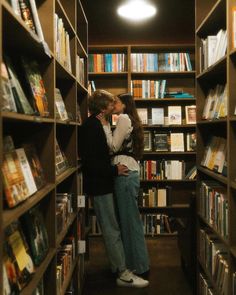 two people are kissing in the middle of a book store filled with shelves full of books