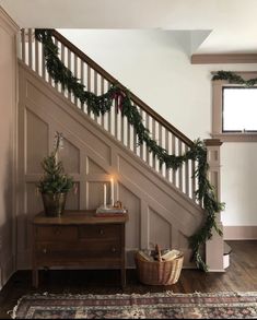 a christmas garland on the banister next to a dresser