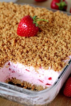 a dessert with strawberries and crumbs in it on a wooden table next to other fruit