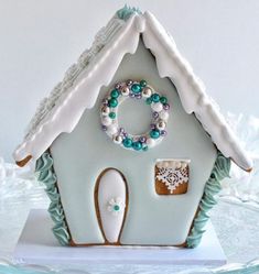 a gingerbread house decorated with frosting, beads and a wreath on the roof