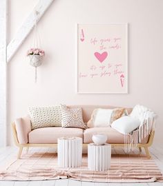 a living room with pink walls and white carpeted flooring is decorated in pastel tones