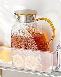 a glass pitcher with liquid in it sitting on a shelf