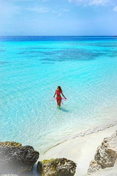 a woman wading in clear blue water on the beach