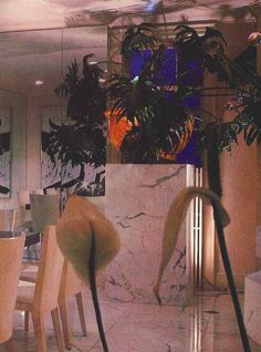 the interior of a restaurant with marble tables and chairs, potted plants on either side