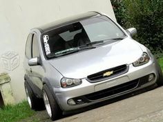 a silver car parked on the side of a road next to a white wall and grass