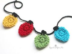 three crocheted ornaments hanging from a string on a white surface with black cord