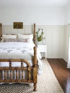 a bedroom with white walls and wooden furniture, including a large bed in the center