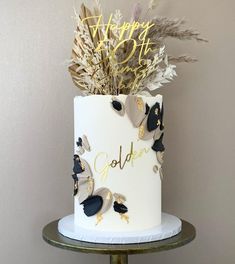 a white and gold birthday cake sitting on top of a table