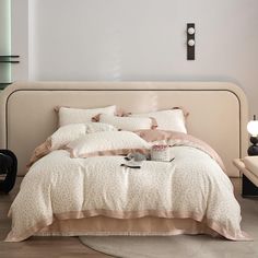 a bed with pillows and blankets on top of it in front of a white wall