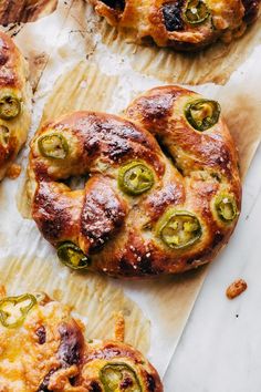 several pastries with peppers and cheese on top of parchment paper next to each other