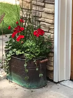 a potted planter filled with red flowers sitting on the side of a house