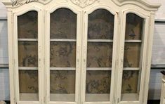 an old white china cabinet with glass doors