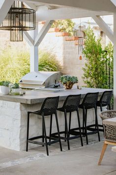 an outdoor kitchen with bar stools next to it