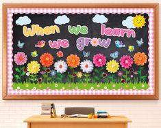 a chalkboard with flowers and butterflies on it in front of a brick wall that says when we learn, we grow