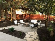 a patio with chairs and fire pit surrounded by trees