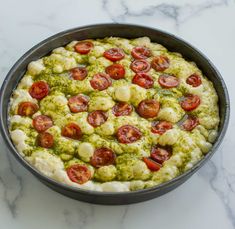 a pizza in a pan with tomatoes and broccoli toppings on the top