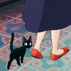 a black cat standing next to a woman's feet on a tile floor with blue and pink tiles