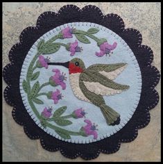 a close up of a patch with a bird and flowers in the center on a stone surface