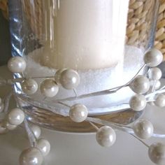 a candle is sitting on a table with some white balls and branches around it in front of a wicker basket