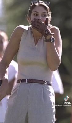 a woman holding her hands up to her mouth while standing in front of other people